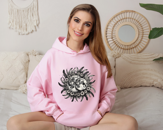 Celebrate the mystery of the night sky with the Twin Moons Hoodie, featuring two radiant moons embraced by a halo of feathers and wildflowers. This enchanting design blends celestial beauty with natural elegance, creating the perfect statement piece for dreamers, stargazers, and lovers of mystical fashion.

Soft, cozy, and effortlessly stylish, this hoodie is ideal for moonlit walks, cozy nights under the stars, or simply carrying a little magic with you wherever you go.

- A must-have for fantasy lovers, c